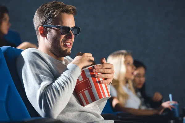 Side view of disgusted man in 3d glasses with popcorn watching film in cinema — Stock Photo