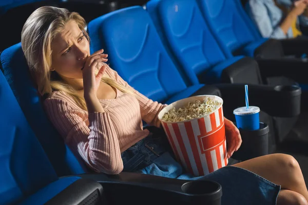 Young emotional woman with popcorn watching film alone in cinema — Stock Photo