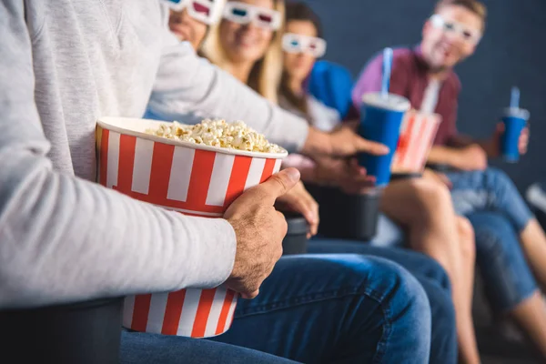 Partial view of multiethnic friends with popcorn watching film together in movie theater — Stock Photo