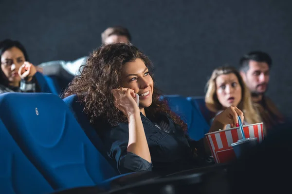 Lächelnde Frau spricht auf Smartphone, während sie Film im Kino anschaut — Stockfoto
