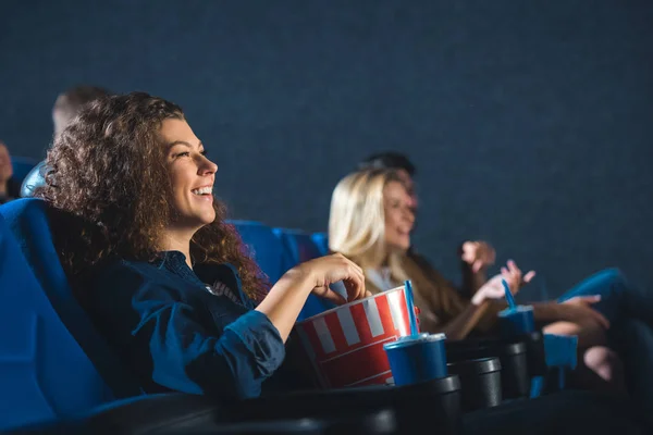 Вид збоку весела жінка з попкорном дивитися фільм у кіно — стокове фото
