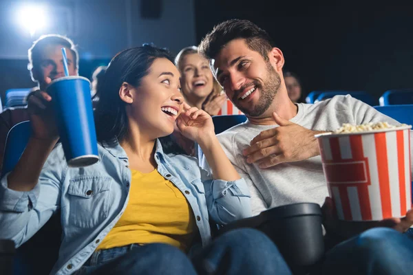 Heureux couple multiculturel avec pop-corn regarder film ensemble dans le cinéma — Photo de stock