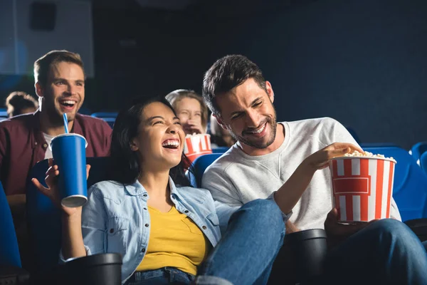 Happy interracial couple with popcorn watching movie together in cinema — Stock Photo