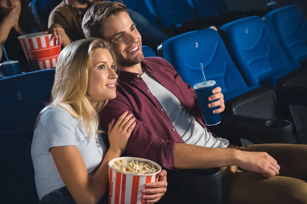 Coppia sorridente con popcorn e bibita guardando film insieme al cinema — Foto stock