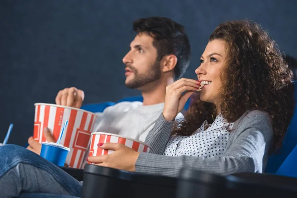 Couple manger du pop-corn tout en regardant un film ensemble au cinéma — Photo de stock