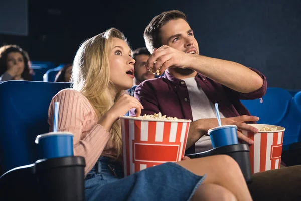 Emotional couple with popcorn watching film together in cinema — Stock Photo