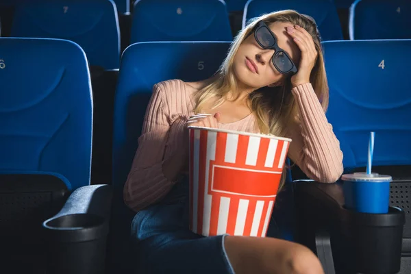 Porträt einer jungen Frau in 3D-Brille mit Popcorn, die sich allein im Kino einen Film ansieht — Stockfoto