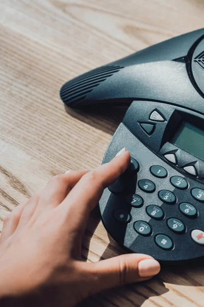 Cropped shot of businesswoman with pink nails pushing button of speakerphone at workplace — Stock Photo