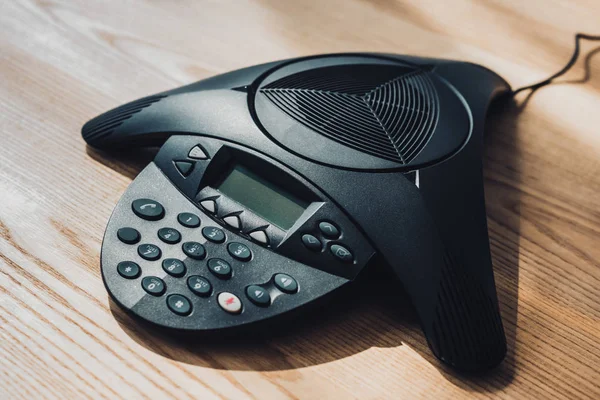 Close-up shot of conference phone on wooden table at office — Stock Photo