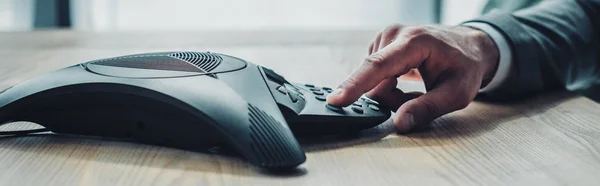 Side view cropped shot of businessman pushing button of conference phone at workplace — Stock Photo