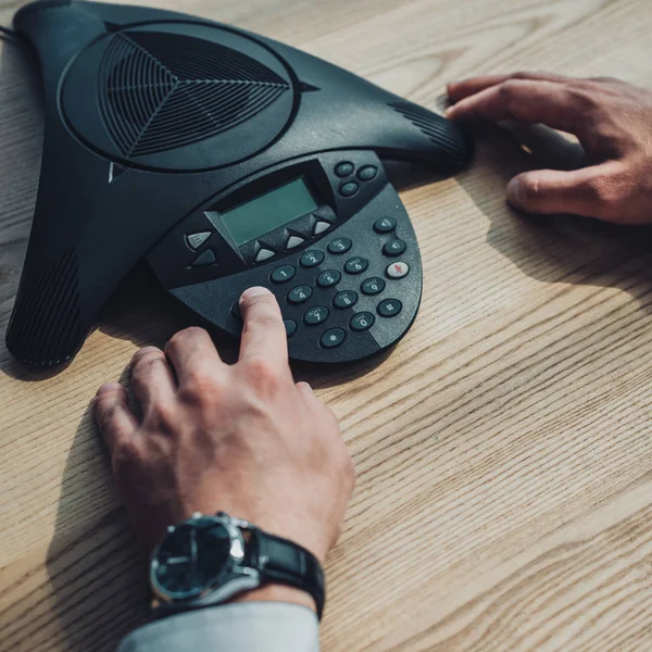 Recortado tiro de hombre de negocios con reloj de pulsera elegante usando altavoz en el lugar de trabajo - foto de stock