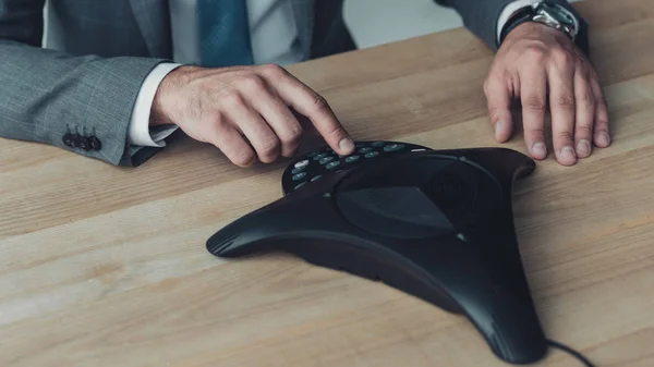 Cropped shot of businessman pushing button of speakerphone at workplace — Stock Photo