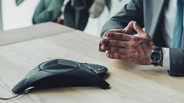 Tiro cortado de homem de negócios sentado e esperando por telefone conferência de chamadas no local de trabalho — Fotografia de Stock