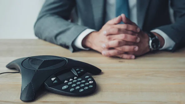 Cropped shot of businessman sitting behind conference phone on table at office — Stock Photo