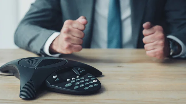 Schnappschuss von Geschäftsmann, der vor Konferenztelefon sitzt und im Büro Fäuste schlägt — Stockfoto