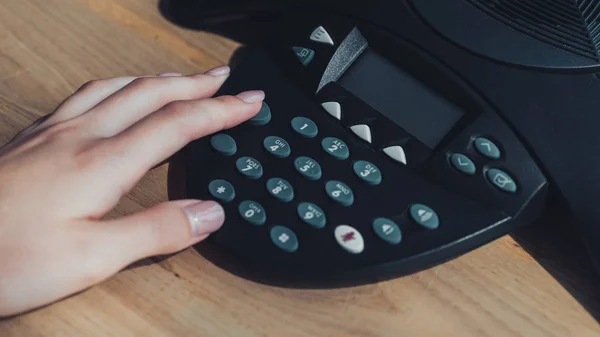 Обрезанный снимок деловой женщины, нажимающей кнопку громкой связи на столе в офисе — стоковое фото