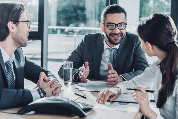 Des gens d'affaires confiants ayant une conversation et utilisant haut-parleur au bureau moderne — Photo de stock