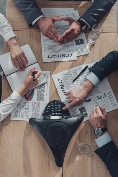 Recortado tiro de gente de negocios que trabajan con documentos y altavoz en la mesa en la oficina moderna - foto de stock