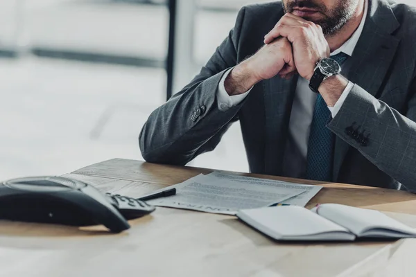 Cropped shot of businessman sitting at workplace with conference phone on table at office — Stock Photo