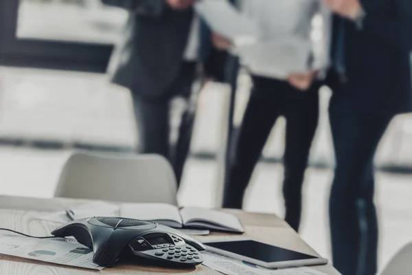 Close-up shot of speakerphone with blurred business people on background at modern office — Stock Photo