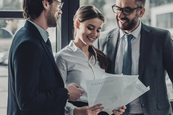 Jeunes gens d'affaires heureux discutant de documents ensemble au bureau — Photo de stock