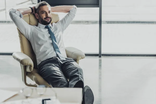 Красивый бизнесмен отдыхает на роскошном кресле в современном офисе — стоковое фото