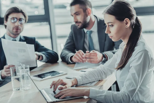 Hermosa joven mujer de negocios que trabaja con el ordenador portátil durante la reunión en la oficina moderna - foto de stock