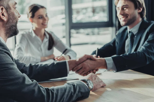 Gente de negocios estrechando la mano durante la reunión en la oficina moderna - foto de stock