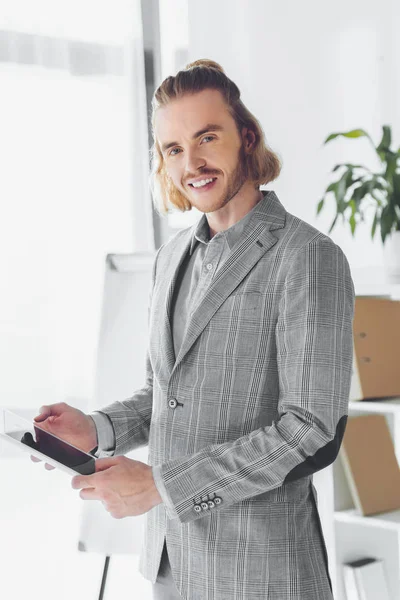 Homme d'affaires souriant debout avec tablette et regardant la caméra — Photo de stock