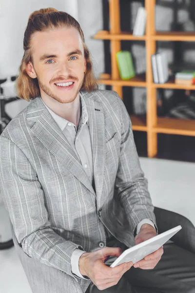 Над головой вид улыбающегося бизнесмена, сидящего в кресле с планшетом — стоковое фото