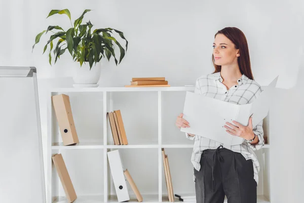 Attractive businesswoman holding folder and looking away — Stock Photo