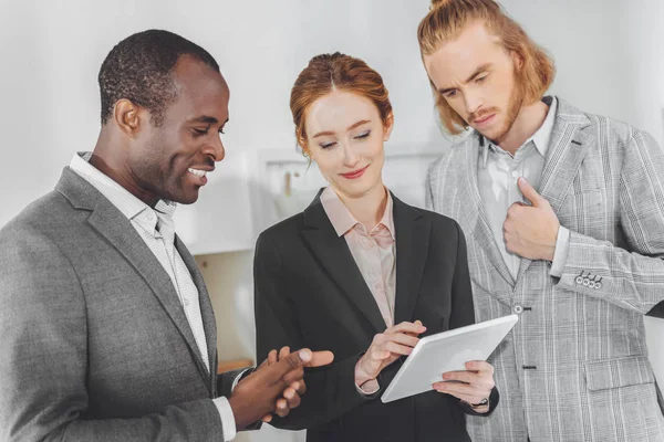 Empresarios multiculturales mirando tableta en la oficina - foto de stock