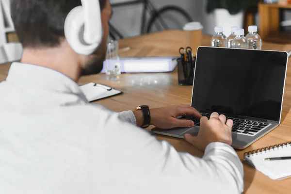 Bel homme d'affaires écoutant de la musique et travaillant sur un ordinateur portable — Photo de stock