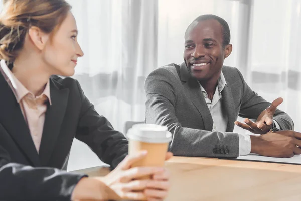 African man smiling to woman with coffe in hands  at office space — Stock Photo