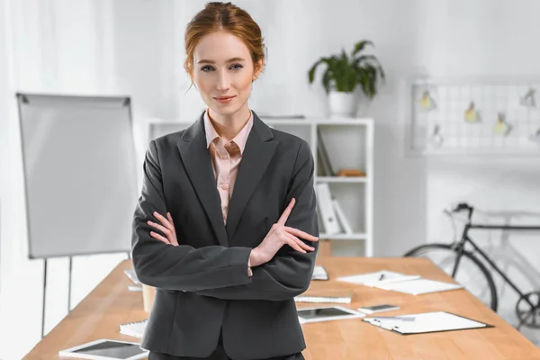 Businesswoman with arms crossed looking at camera at office space — Stock Photo