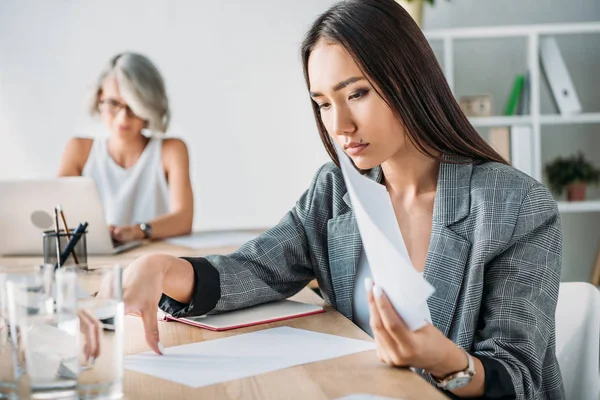 Attractive asian businesswoman reading documents in office — Stock Photo