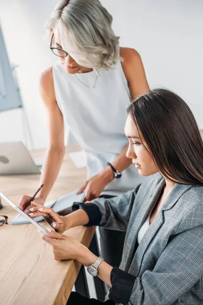 Multicultural businesswomen looking at tablet in office — Stock Photo