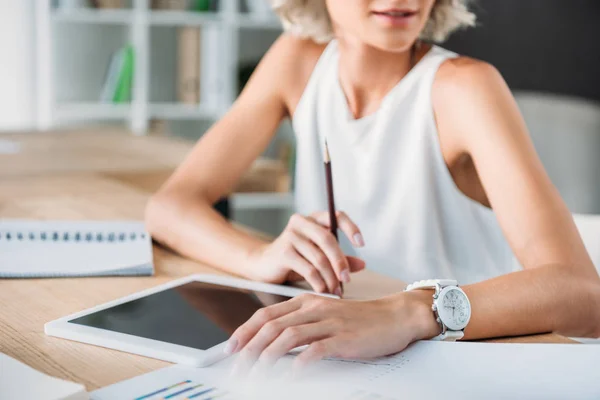 Imagen recortada de la mujer de negocios sentada en la mesa con la tableta en la oficina - foto de stock