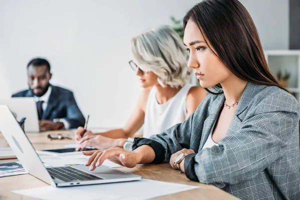 Vista laterale di imprenditori multietnici che lavorano a tavola in ufficio — Foto stock