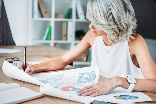 Mujer de negocios caucásica escribiendo algo en la mesa en la oficina - foto de stock