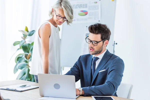 Junge Geschäftsleute schauen am Arbeitsplatz auf Laptop — Stockfoto