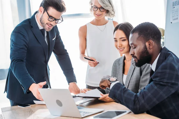 Happy multicultural businesspeople working on project in office and looking at laptop — Stock Photo