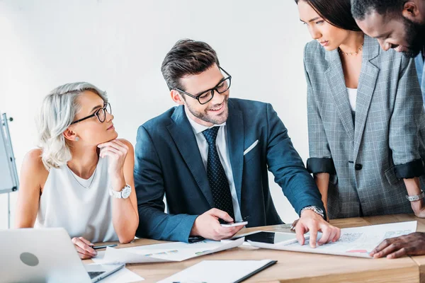 Entrepreneurs multiculturels travaillant sur le projet dans le bureau et debout près de la table avec des documents — Photo de stock