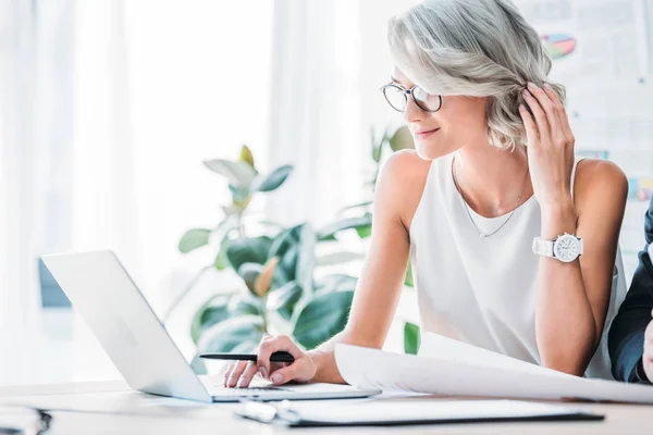 Vista lateral da bela mulher de negócios caucasiana usando laptop no escritório — Fotografia de Stock