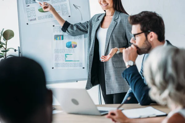 Abgeschnittenes Bild einer lächelnden Geschäftsfrau, die während eines Treffens im Büro auf Flipchart zeigt — Stockfoto