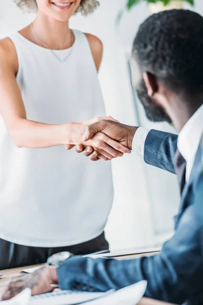 Imagem cortada de empresários multiculturais apertando as mãos no escritório — Fotografia de Stock