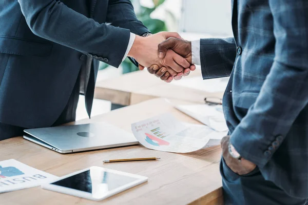 Imagen recortada de empresarios multiculturales estrechando la mano en la oficina - foto de stock