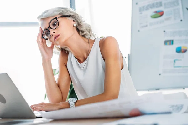 Schöne müde Geschäftsfrau schaut auf Laptop im Büro — Stockfoto