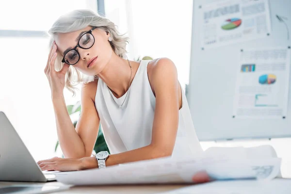 Beautiful tired businesswoman looking at documents in office — Stock Photo