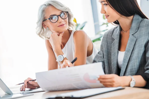 Attractive multicultural businesswomen working in office and looking at each other — Stock Photo